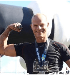 Bild på Henrik som är VD för Järv Äventry. Han spänner högre biceps och ler mot kameran efter att ha klarat av ett lopp.